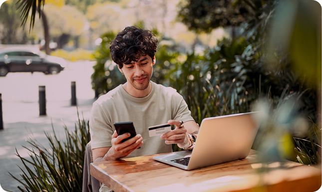 Picture of person using devices and looking at credit card.